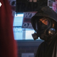 Y: The Last Man's Yorrick is wearing his gas mask and black raincoat while standing in front of art of his President mother being called a liar.